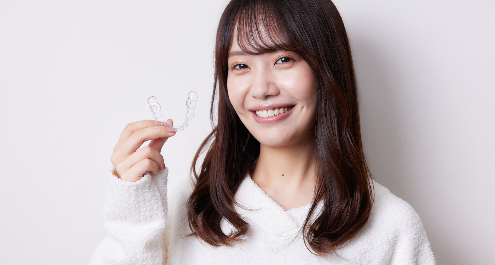 マウスピース型矯正装置を持つ女性